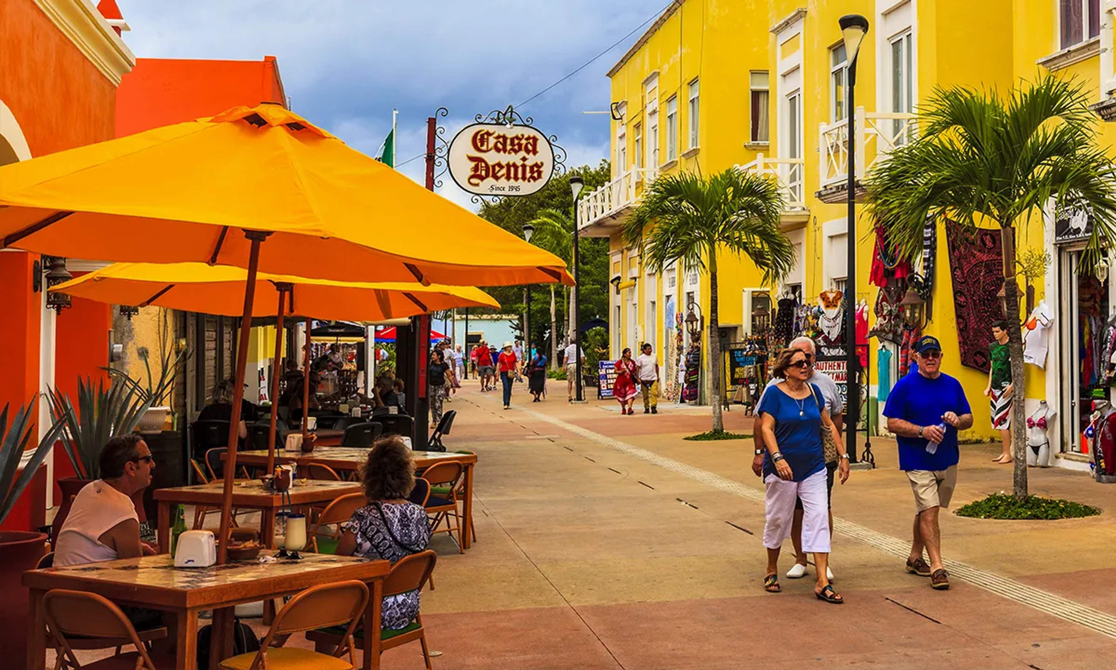 Calle vibrante en Cozumel con fachadas coloridas, tiendas locales y cafeterías, ideal para disfrutar la cultura caribeña.