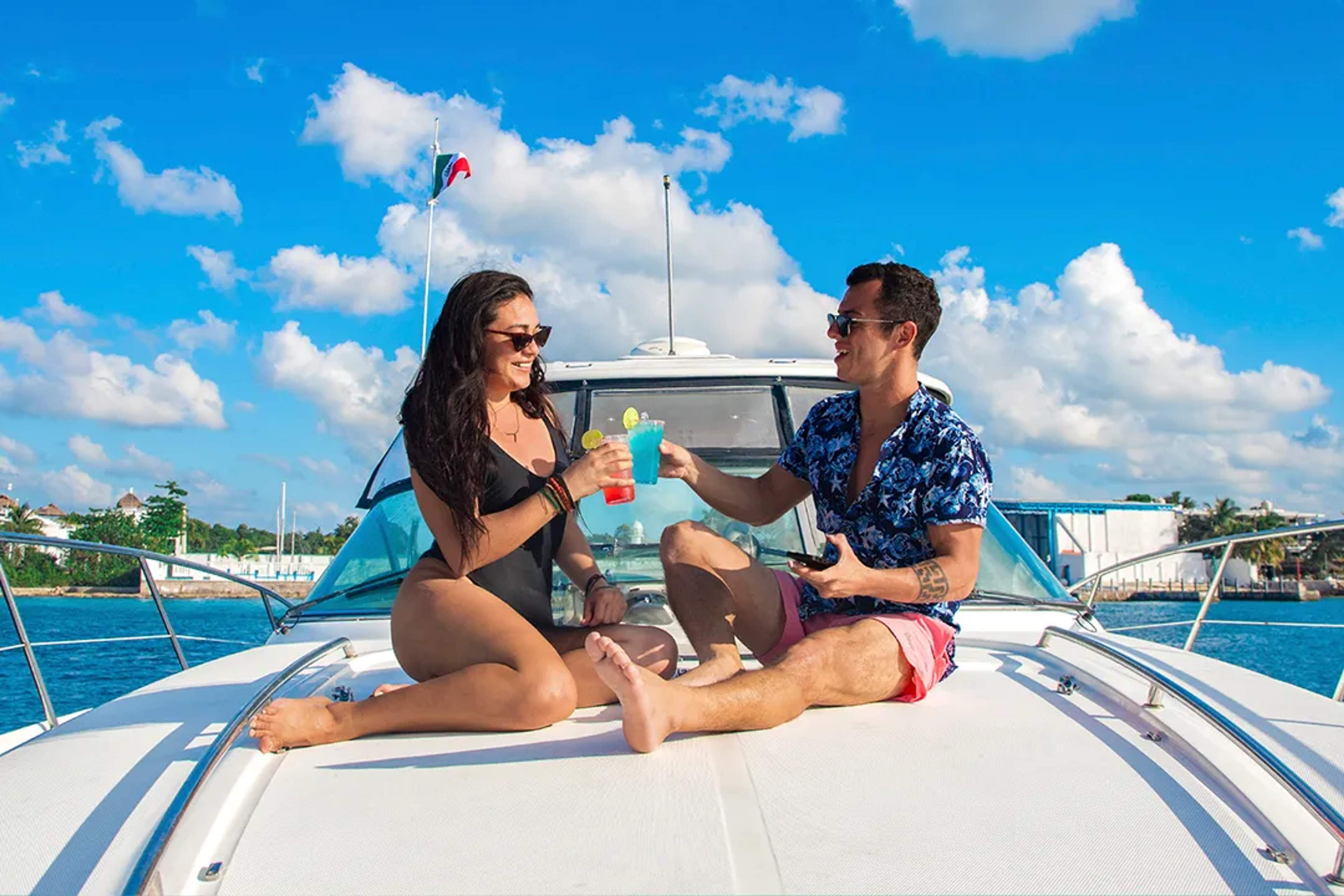 Couple toasting with cocktails aboard a private yacht in Cancún, enjoying a relaxed luxury cruise on turquoise waters