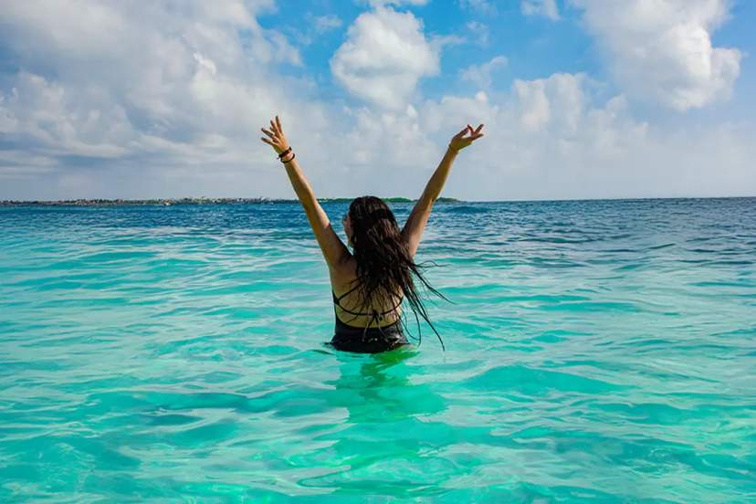 Woman swimming in turquoise Caribbean waters during an Isla Mujeres catamaran and snorkeling tour