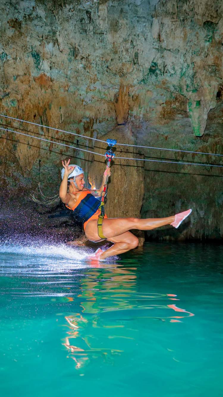 Chica deslizándose en una tirolesa en un cenote subterráneo en Cancún.