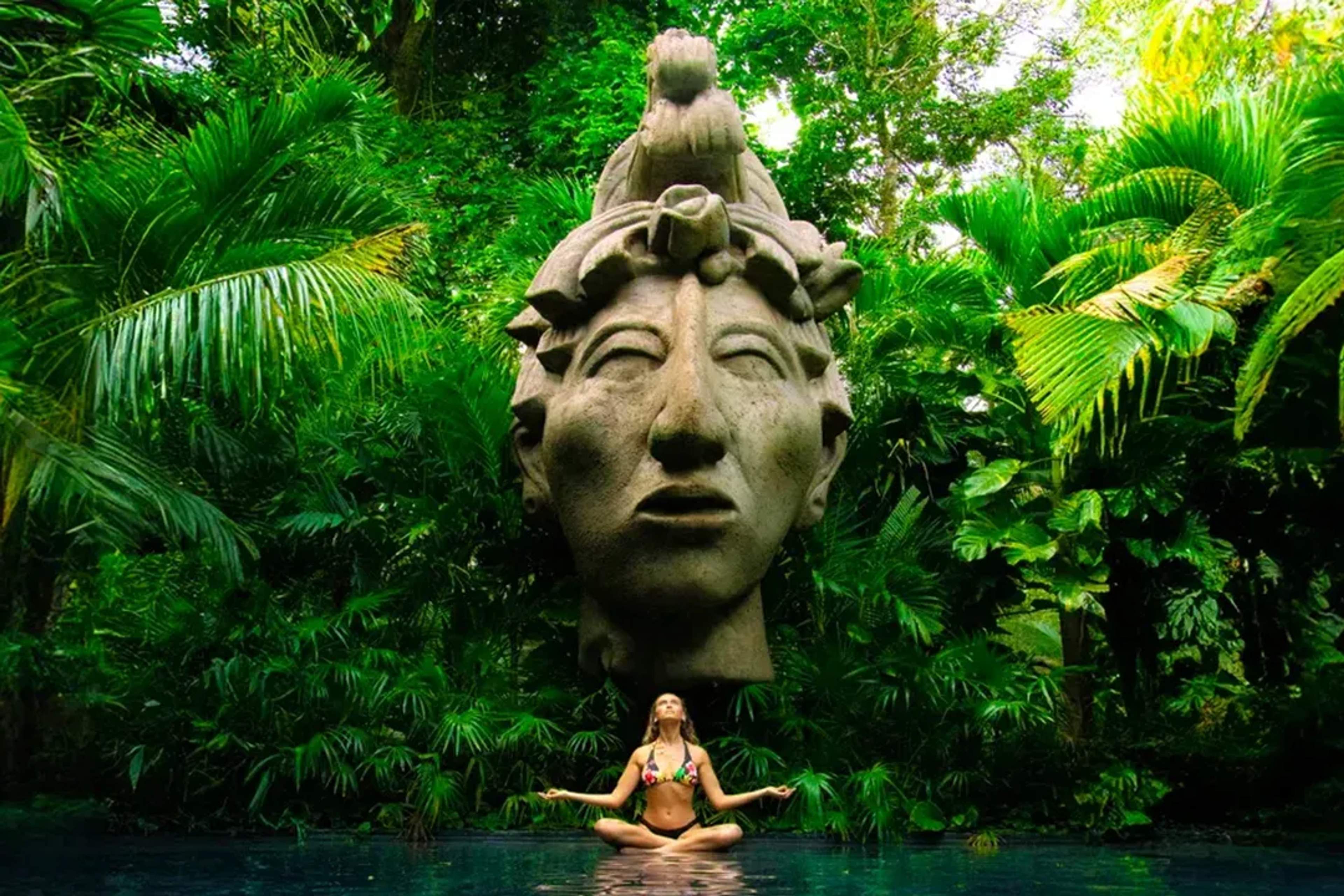 Jungle goddess statue rises above lagoon as a woman meditates in nature at Vallarta Adventures