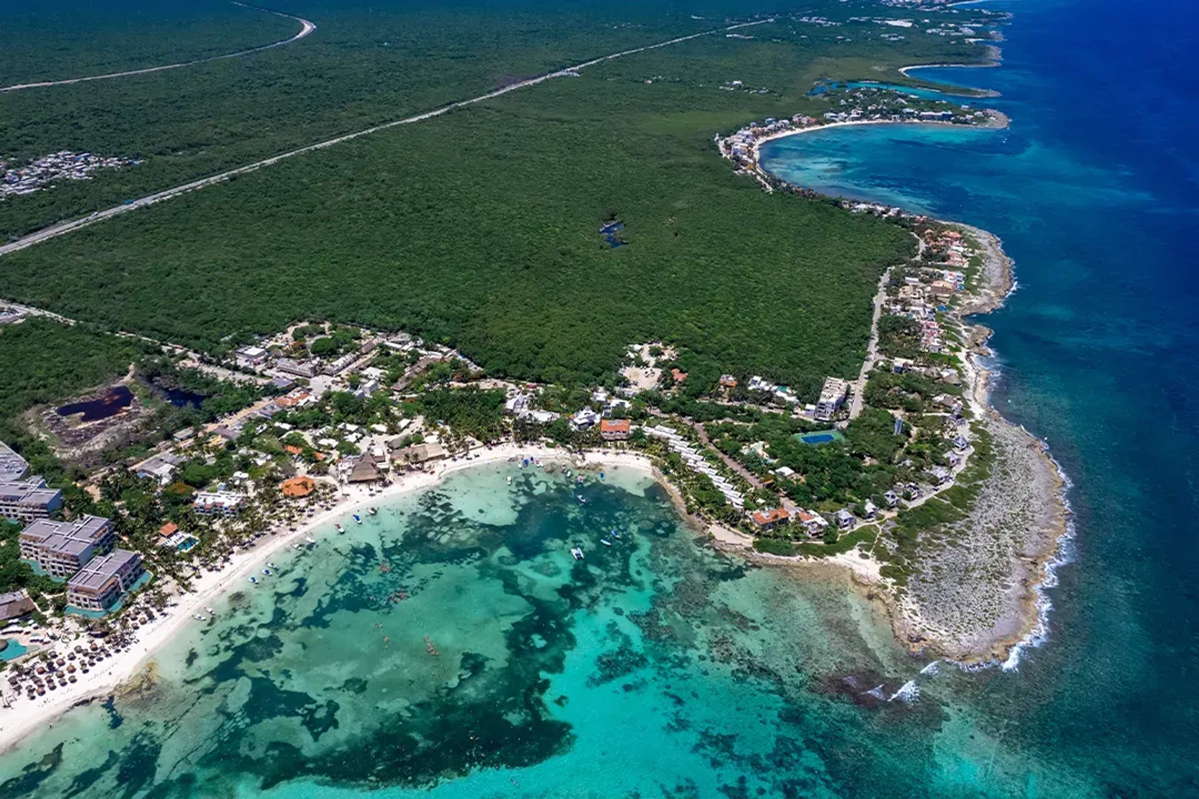 Vista aérea de la Riviera Maya, destacando aguas turquesas, exuberante vegetación y vibrantes comunidades costeras.
