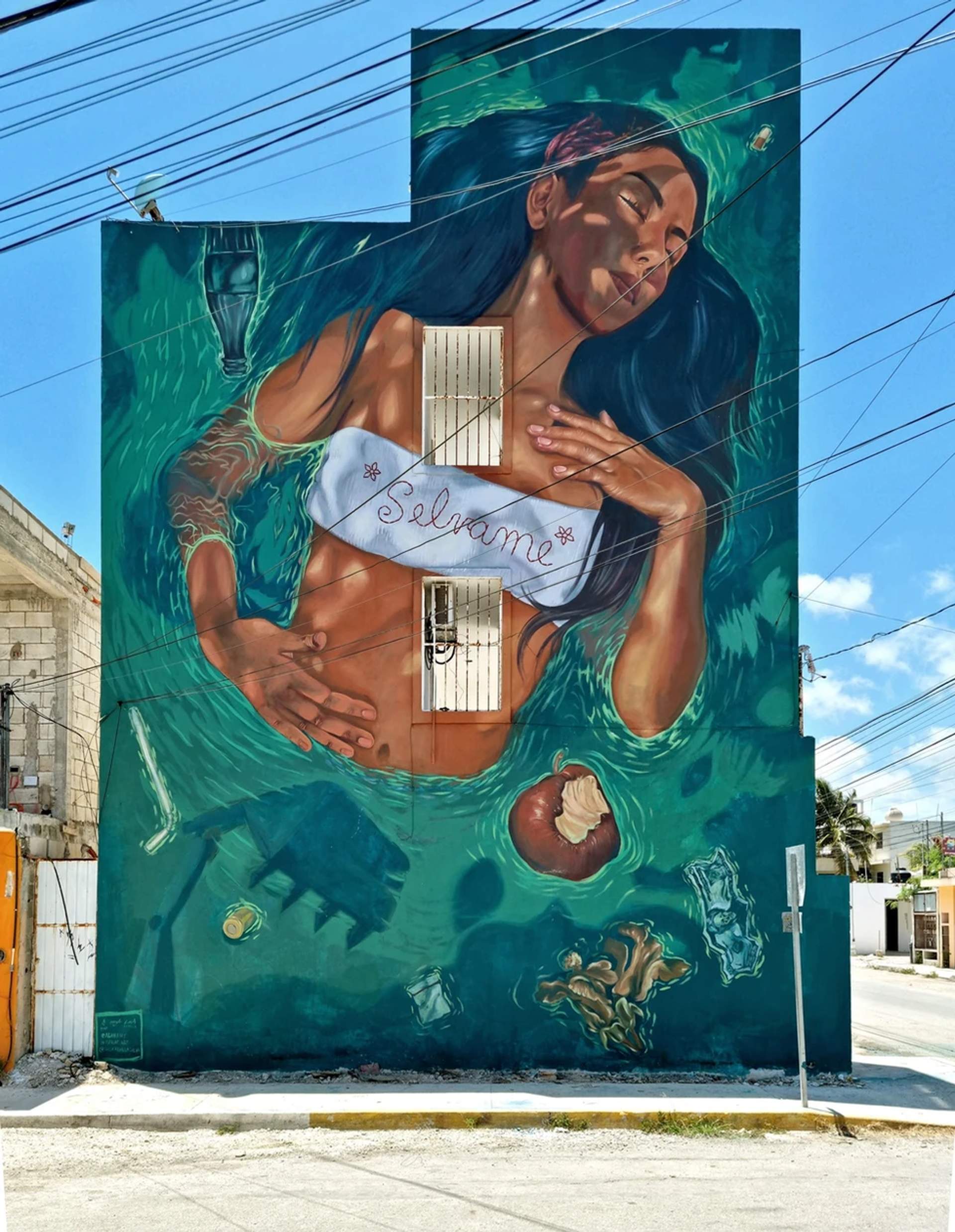 Mural of a woman floating in water, surrounded by trash, with “Sélvame” written on her top.