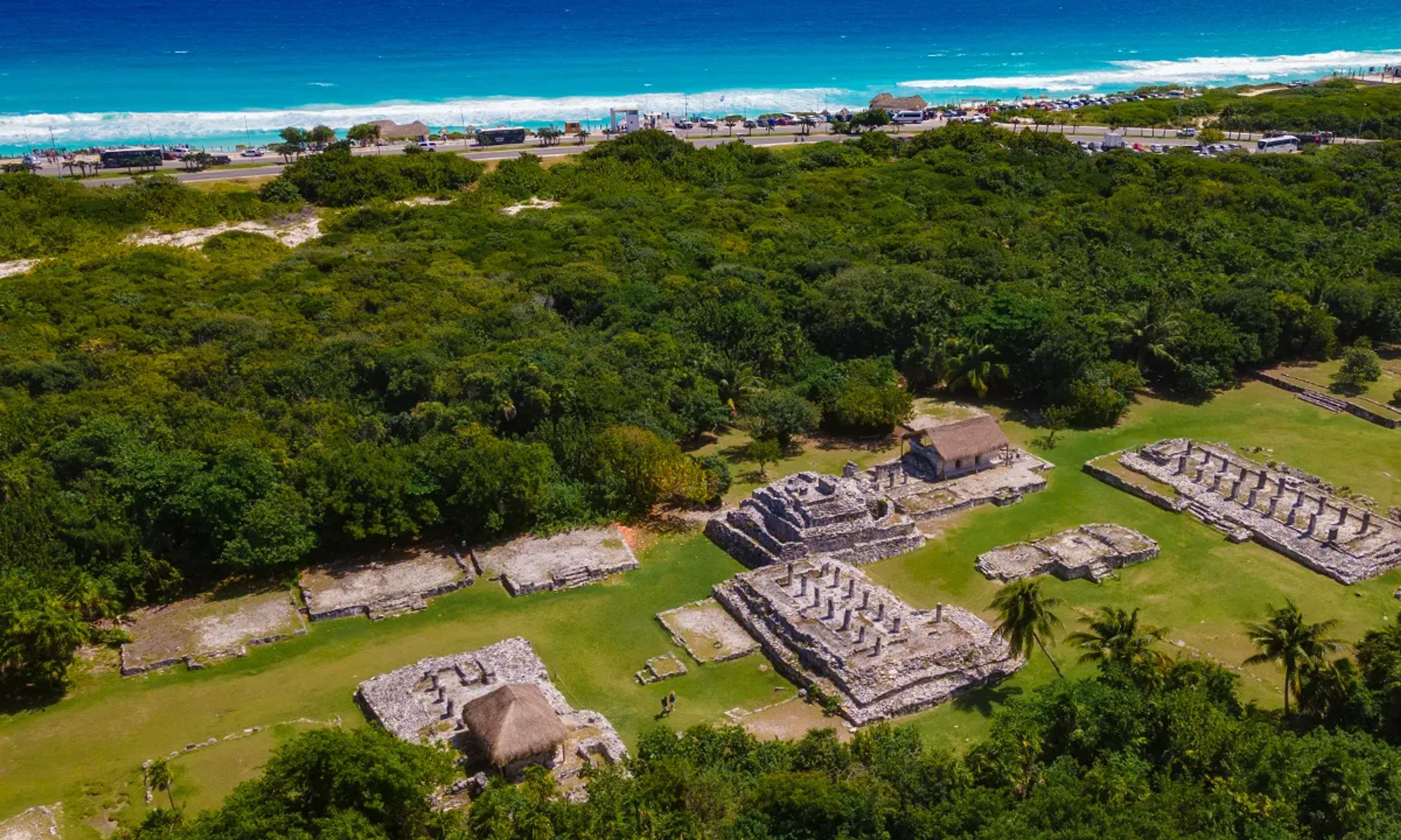 Aerial view of Mayan ruins surrounded by jungle near the Caribbean Sea, showcasing history and natural beauty.