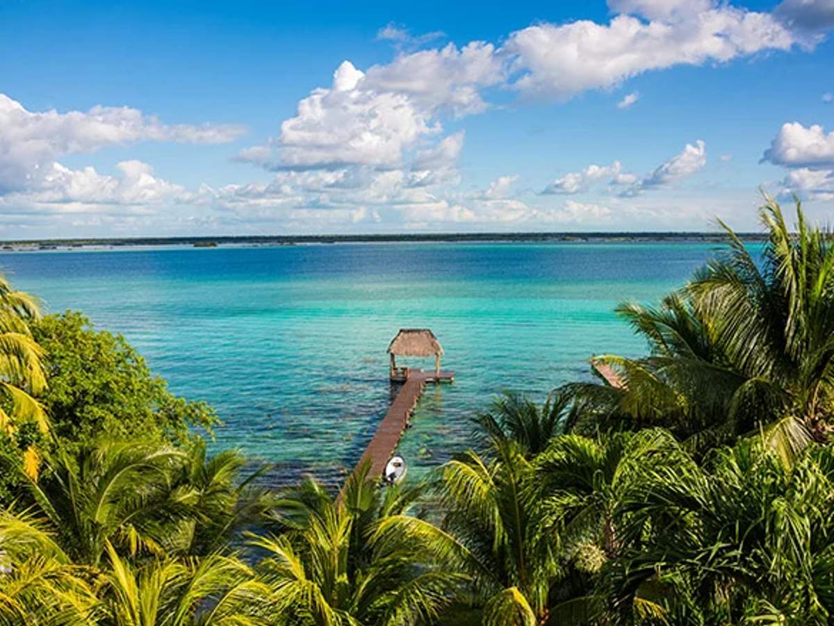 Tranquil pier in Cancun during hurricane season, surrounded by lush greenery and turquoise waters.
