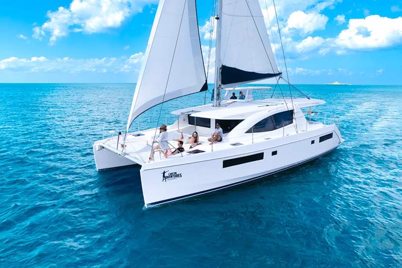 Luxury catamaran tour in Cancun with guests sailing over turquoise Caribbean waters under sunny skies