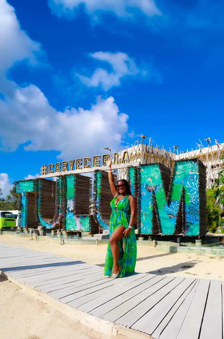 Woman posing in front of the Tulum sign, a photogenic and popular spot for tourists.