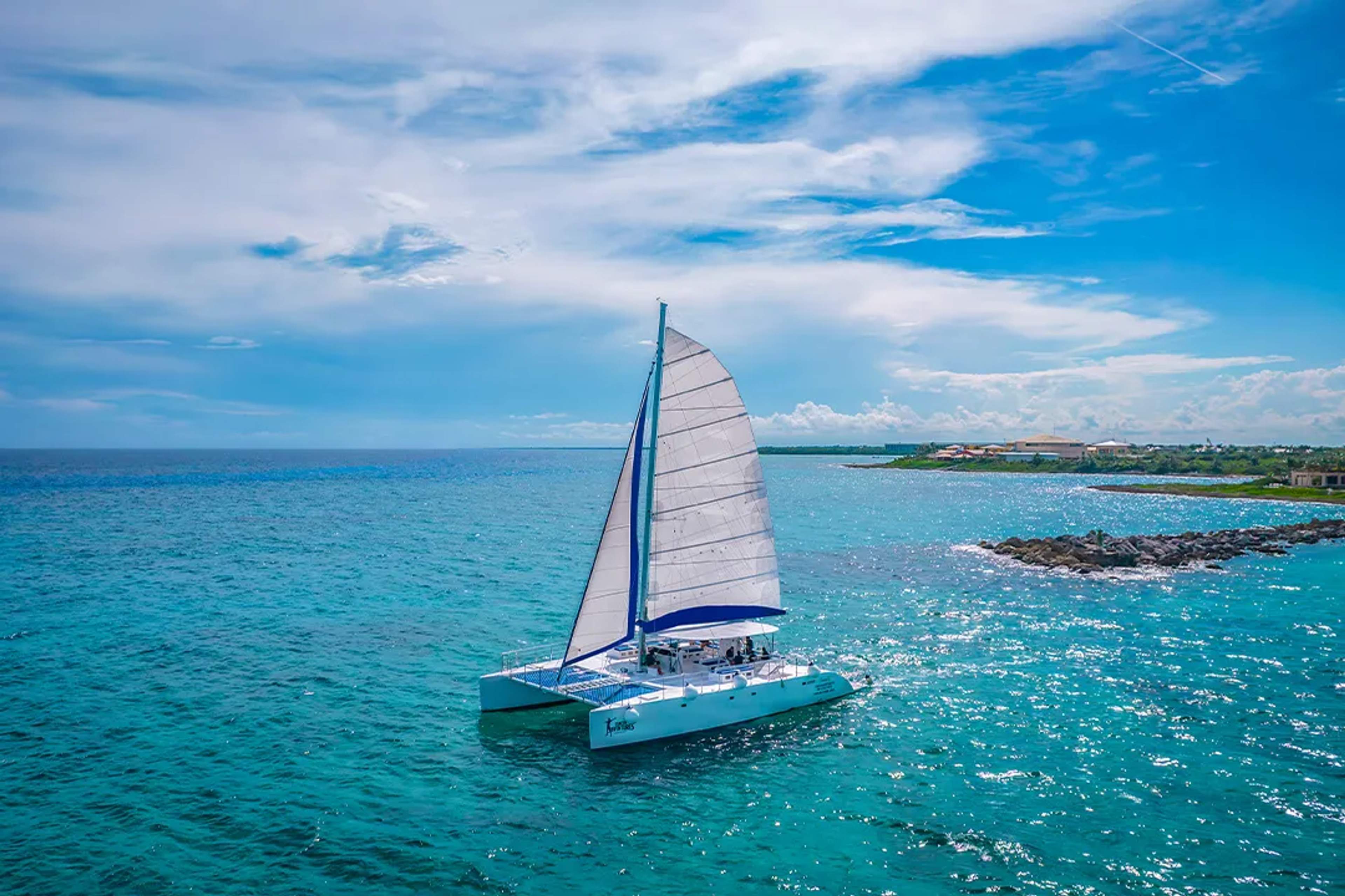 Catamaran sailing in Cancun's blue waters under a clear sky, near the coast.
