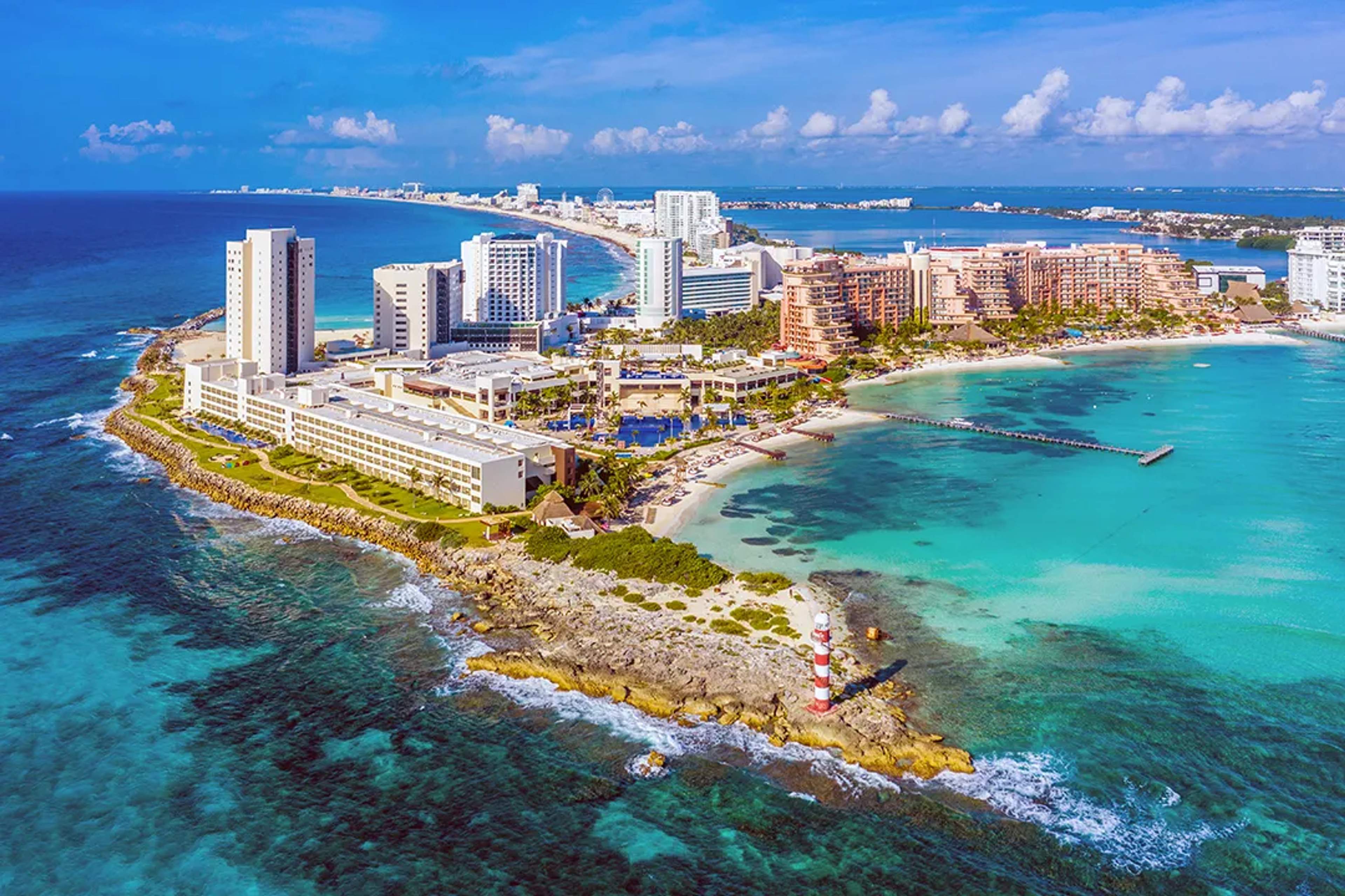 Vista aérea de la Zona Hotelera de Cancún con mar turquesa, hoteles y faro sobre la costa caribeña