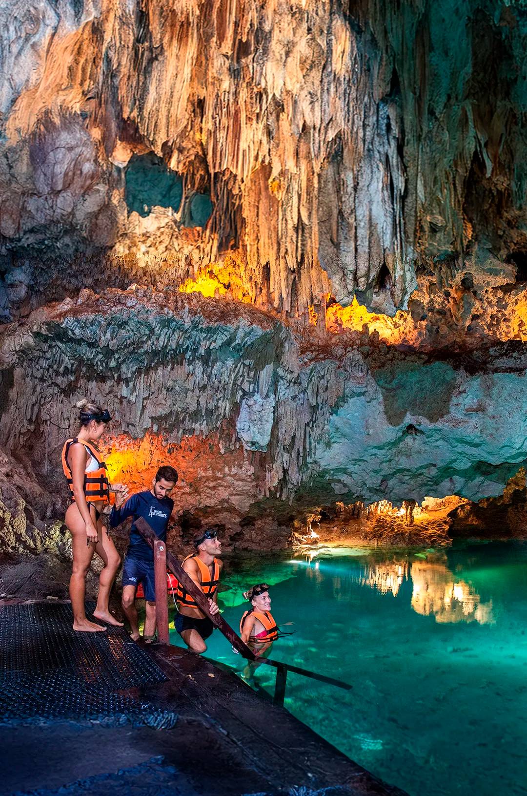 Grupo de viajeros adentrándose bajo tierra para explorar un cenote cerrado.