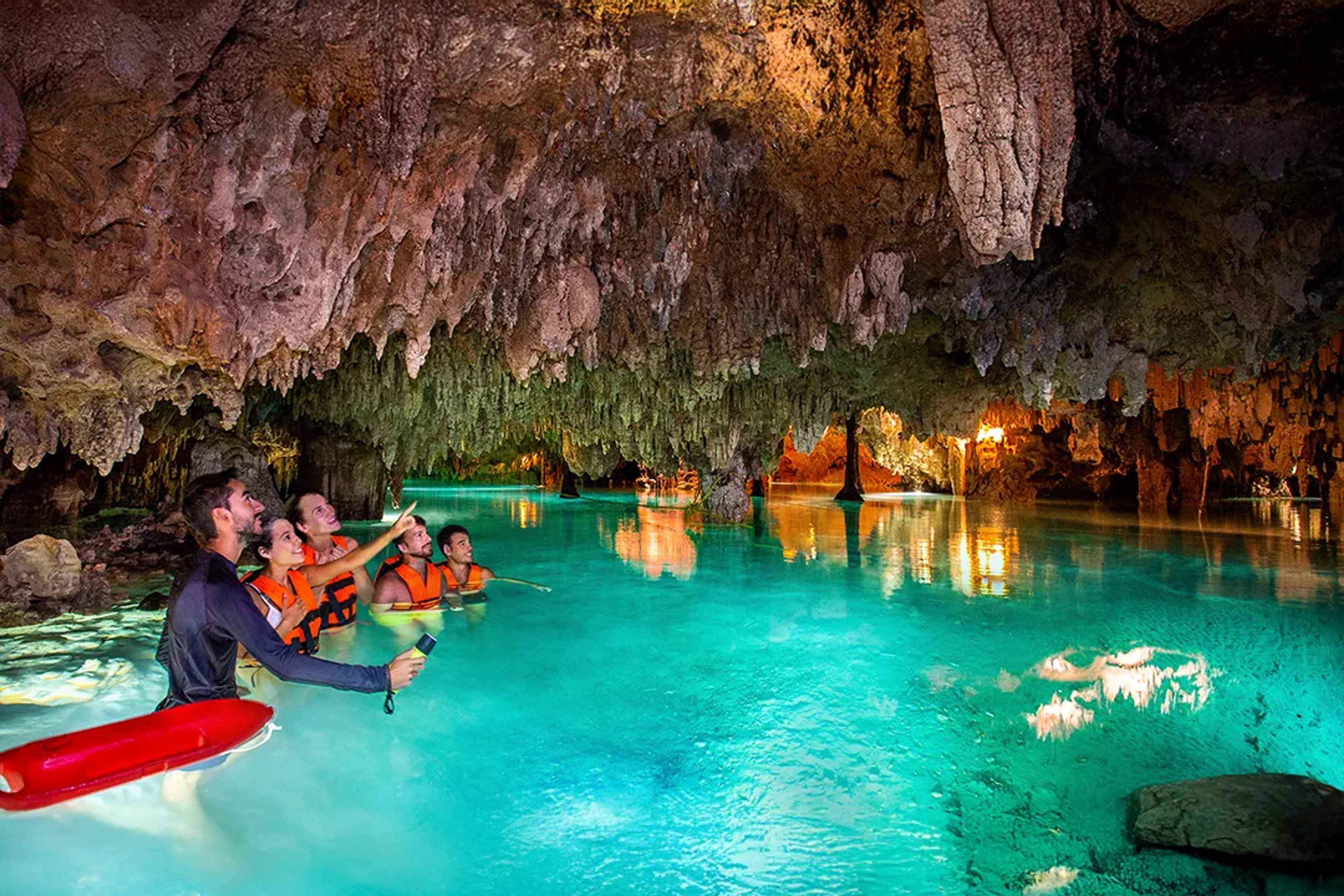 Viajeros explorando un cenote de aguas cristalinas en tour de aventura en Riviera Maya, México