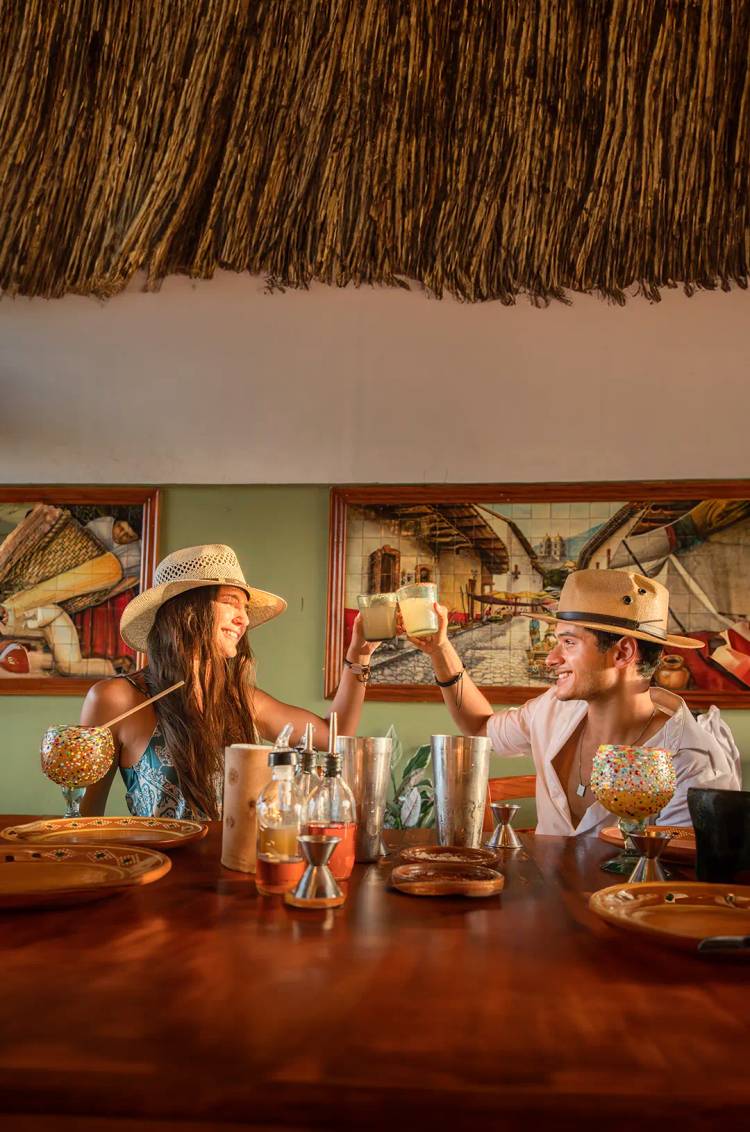 Pareja brindando con cocteles tropicales durante un Food Tour en Cancún.