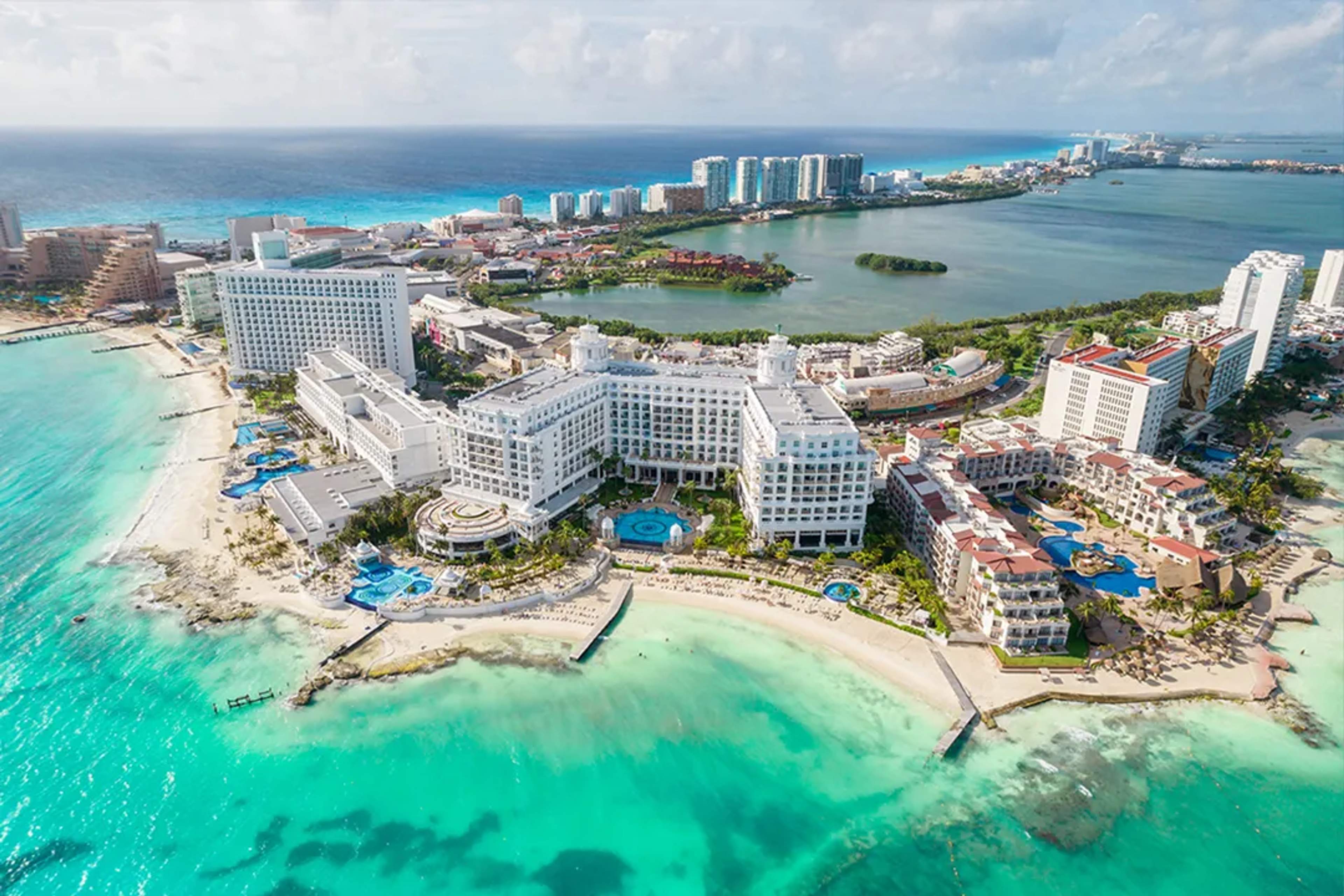 Vista aérea de lujosos resorts frente al mar en la Zona Hotelera de Cancún, con aguas turquesa.