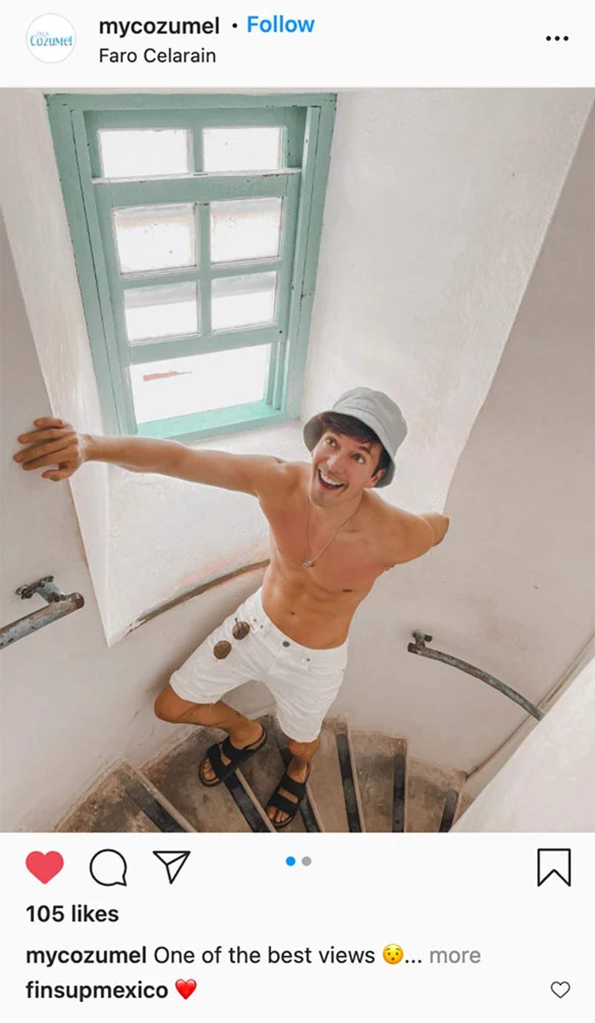 A man posing on the spiral staircase inside Faro Celarain lighthouse in Cozumel, with a window providing natural light.