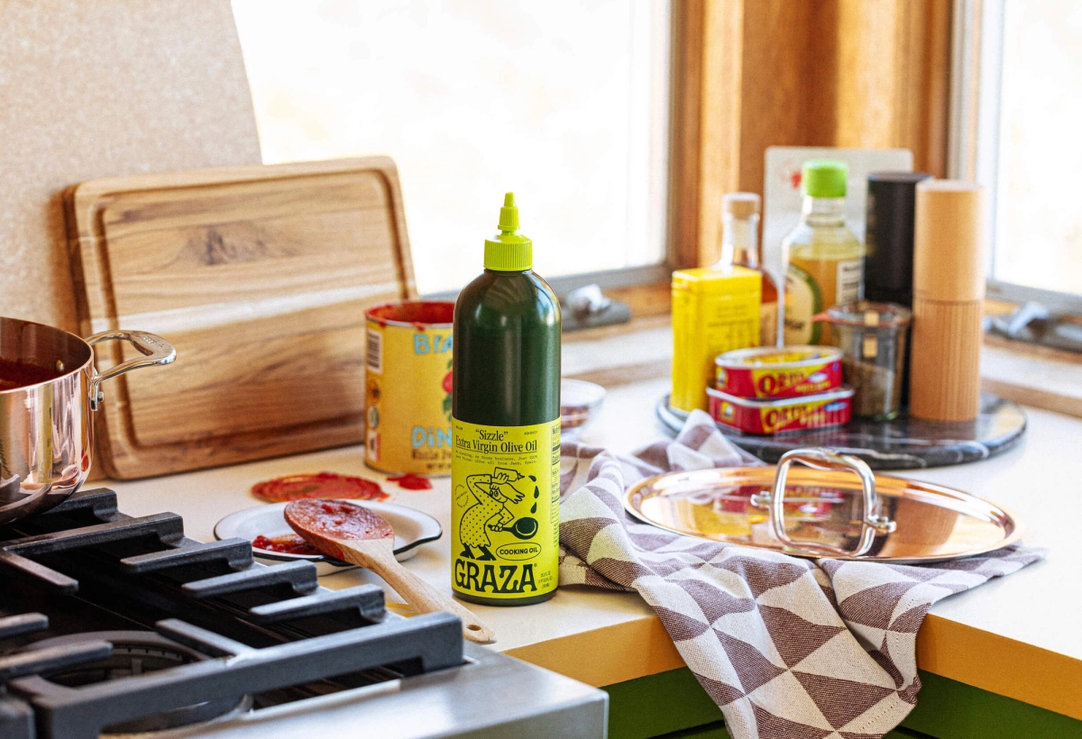 Graza Sizzle squeeze bottle with ingredients on countertop in kitchen setting