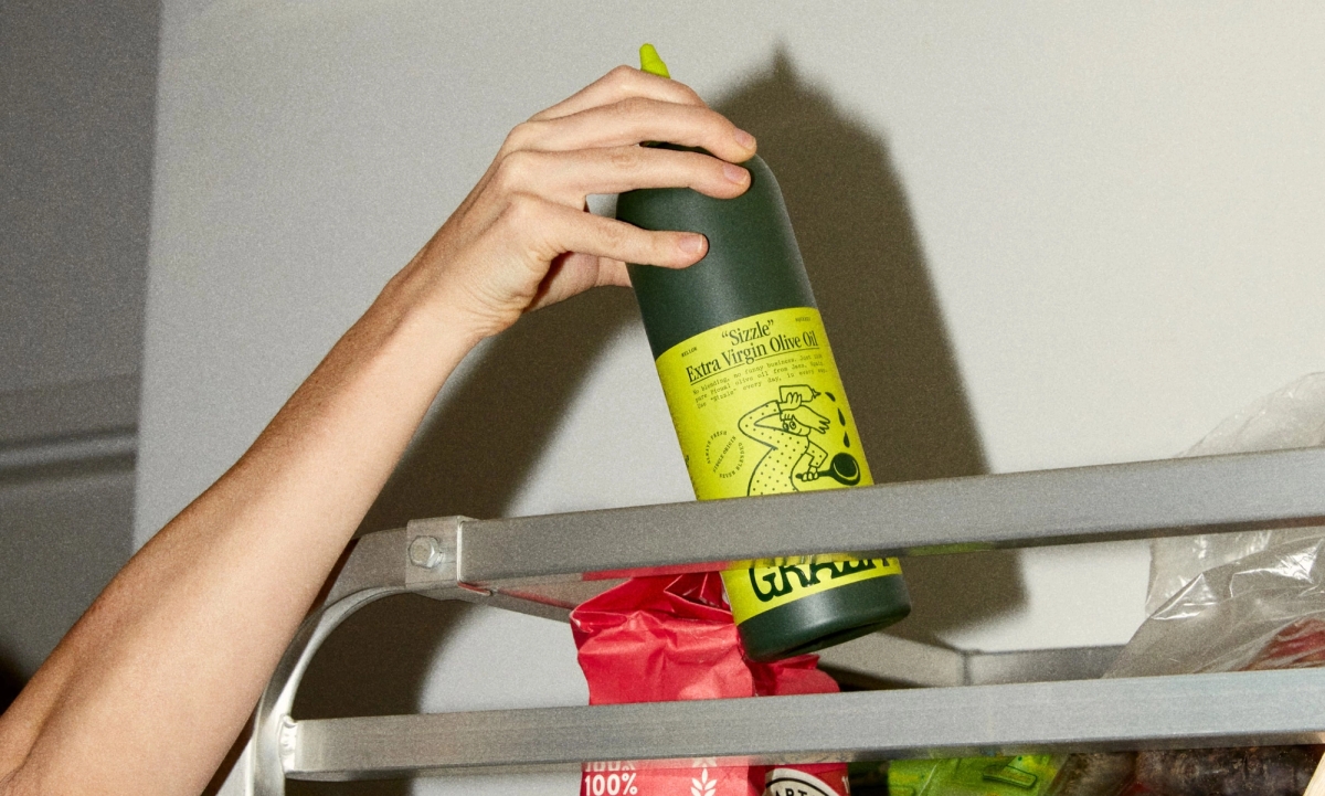 Graza squeeze bottle being grabbed from top shelf in a commercial kitchen