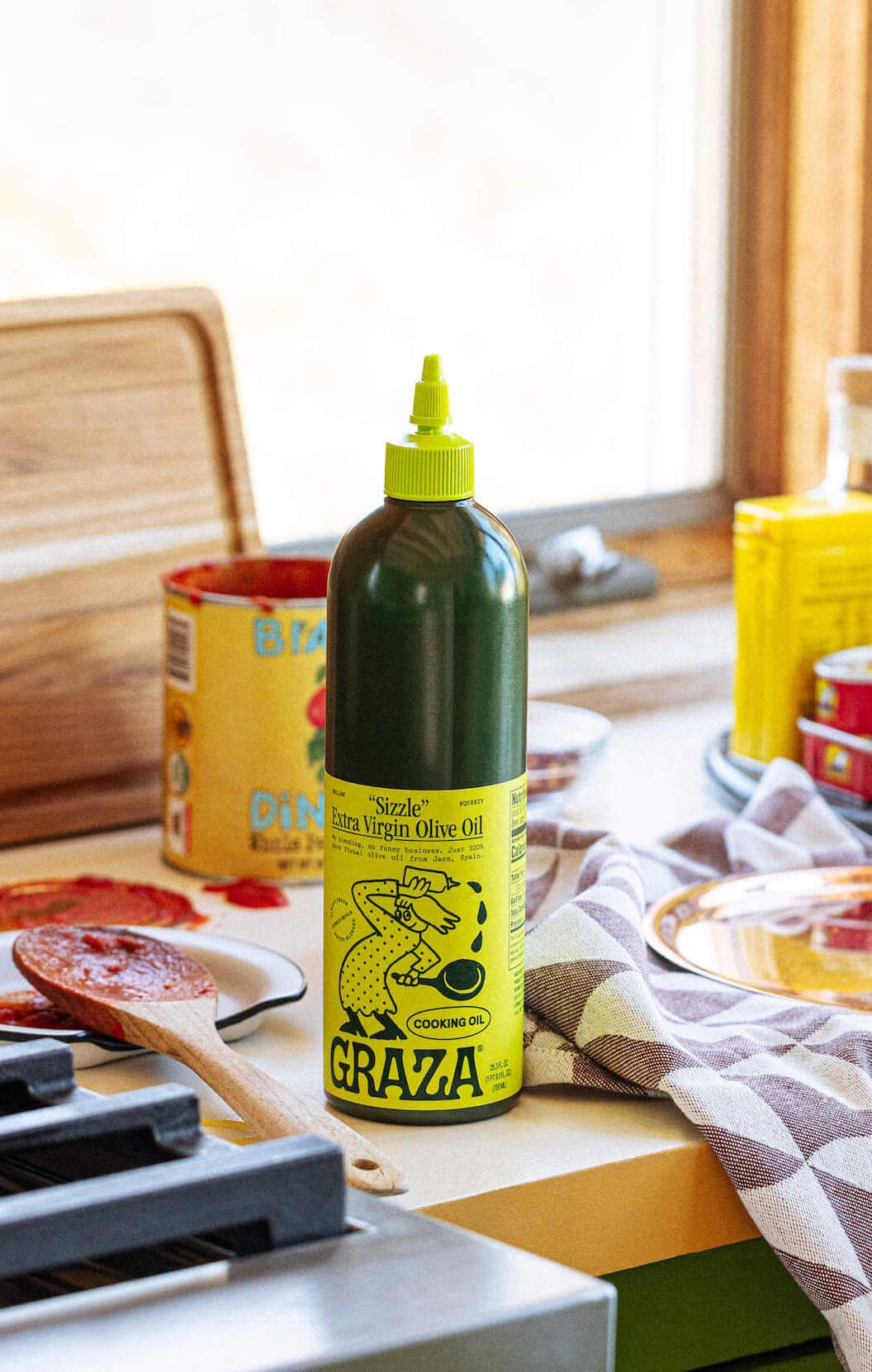 Graza Sizzle squeeze bottle with ingredients on countertop in kitchen setting