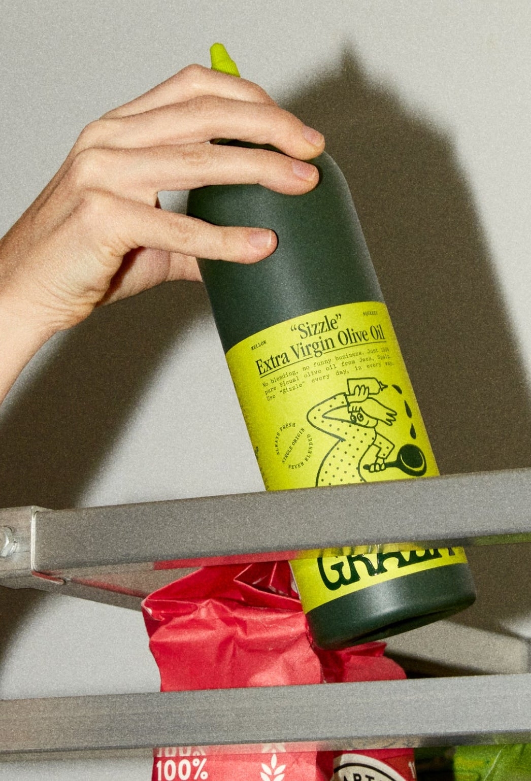 Graza squeeze bottle being grabbed from top shelf in a commercial kitchen
