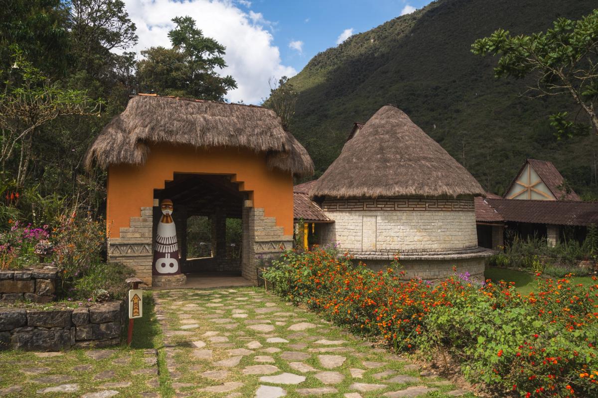 Entrance to the Museo Leymebamba, with thatched roofs and a round stone building modeled on Chachapoya architecture, set against forested hills