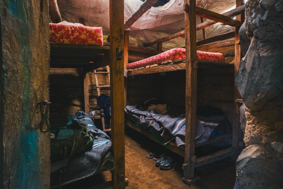 Wooden bunk beds with foam mattresses and blankets inside the rustic basecamp lodge at Laguna de los Cóndores