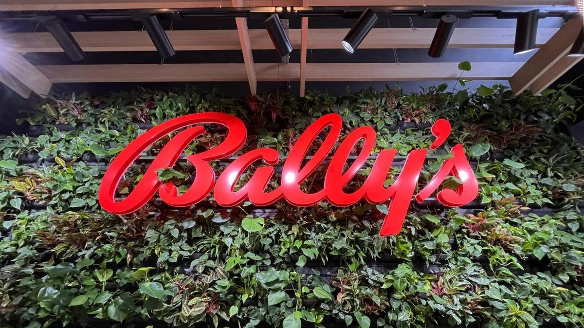 A large red Bally's sign mounted on a lush green wall of living plants.