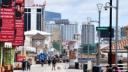 People walking along the Atlantic City boardwalk with casino hotels like Hard Rock in the background.