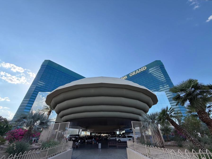The tiered circular entrance canopy of the MGM Grand hotel in Las Vegas, with its green glass towers rising into a blue sky.