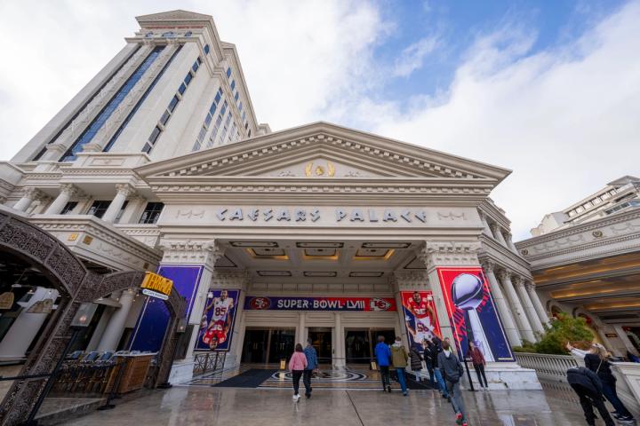 People walk toward the entrance of Caesars Palace in Las Vegas, decorated with Super Bowl LVIII banners.