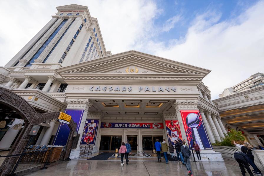 People walk toward the entrance of Caesars Palace in Las Vegas, decorated with Super Bowl LVIII banners.