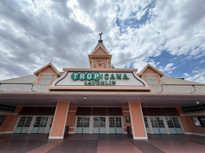 The entrance of the Tropicana Laughlin casino, featuring a clock tower and Victorian-style architecture under a cloudy sky.