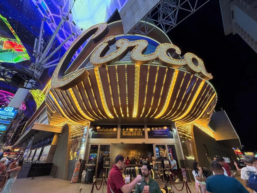 Brightly lit neon entrance of the Circa Resort & Casino in Las Vegas at night, with people standing near the doors.