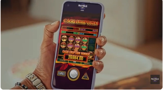 Hand holding a smartphone showing a $26,984.00 slot win