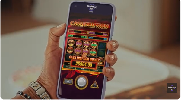 Hand holding a smartphone showing a $26,984.00 slot win