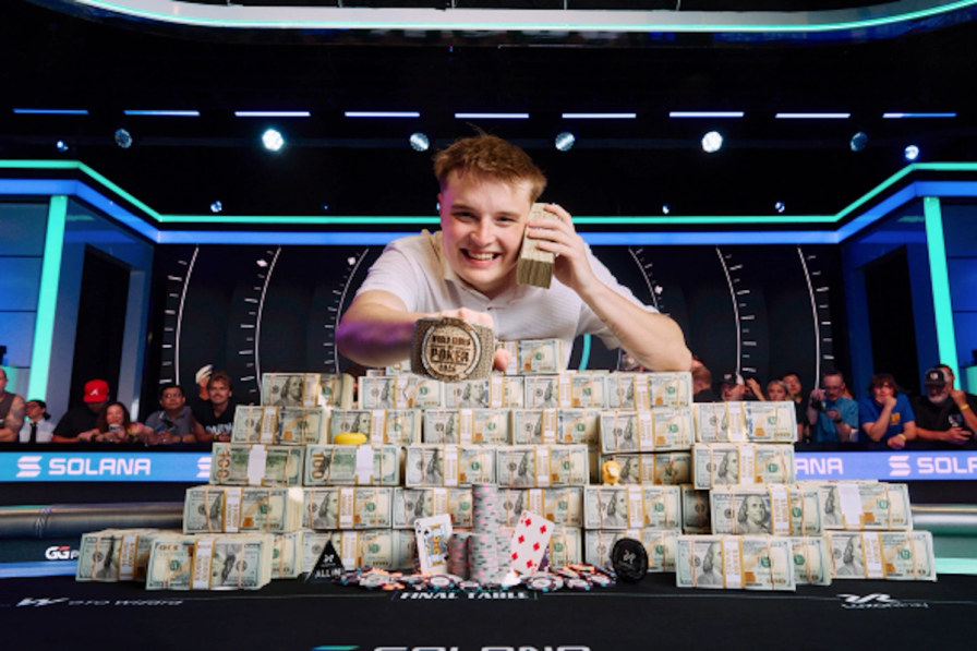 Lucas Jumalon smiles behind a massive pyramid of cash, holding a stack to his ear and displaying his WSOP championship bracelet.