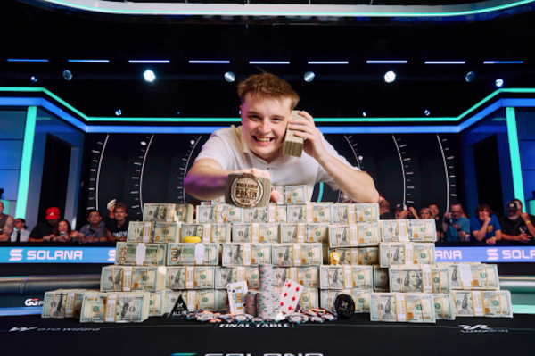 Lucas Jumalon smiles behind a massive pyramid of cash, holding a stack to his ear and displaying his WSOP championship bracelet.
