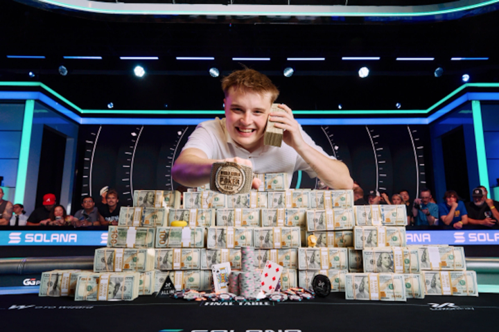 Lucas Jumalon smiles behind a massive pyramid of cash, holding a stack to his ear and displaying his WSOP championship bracelet.