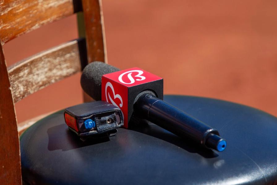 A Bally Sports microphone with a red logo flag rests on a black stool.