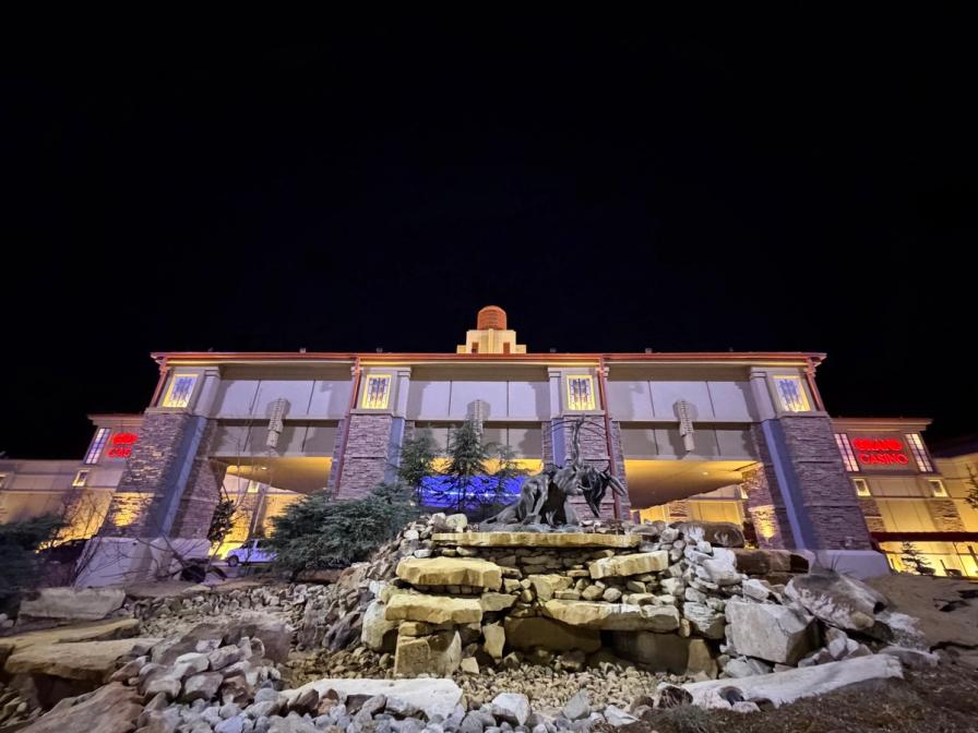 The illuminated Grand Casino building at night, fronted by a rocky waterfall feature and a bronze statue.