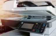Close-up of an office copier and scanner machine with the lid slightly open.