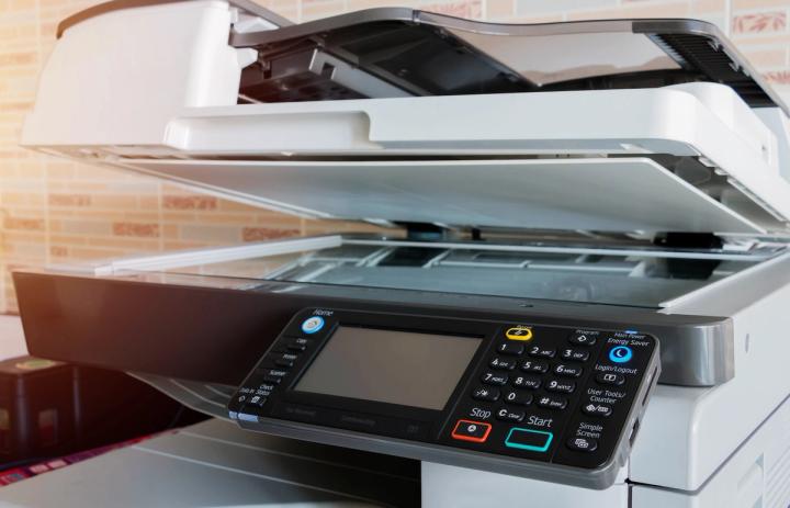 Close-up of an office copier and scanner machine with the lid slightly open.