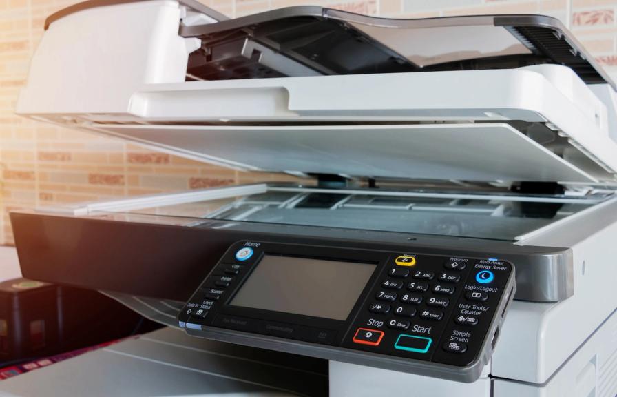 Close-up of an office copier and scanner machine with the lid slightly open.