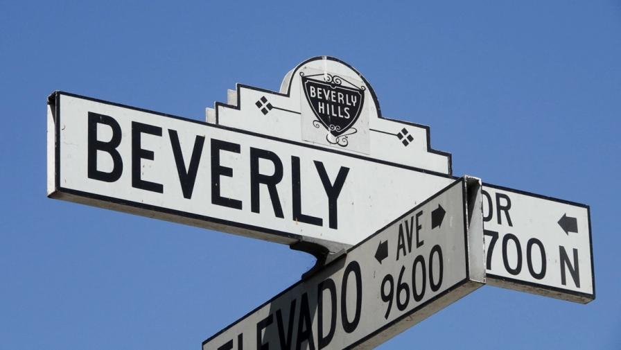 A street sign for Beverly Dr and Elevado Ave in Beverly Hills, California, set against a clear blue sky.