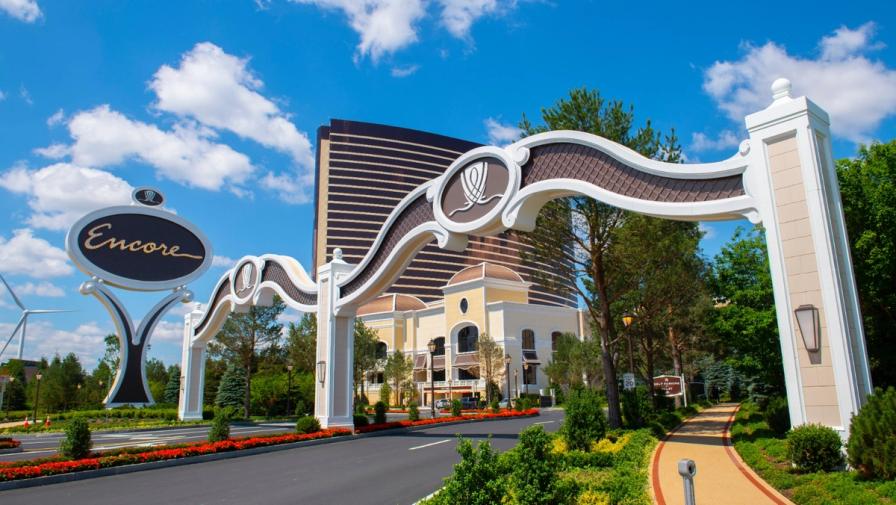 The entrance archway and sign of the Encore Boston Harbor resort with its bronze hotel tower in the background.
