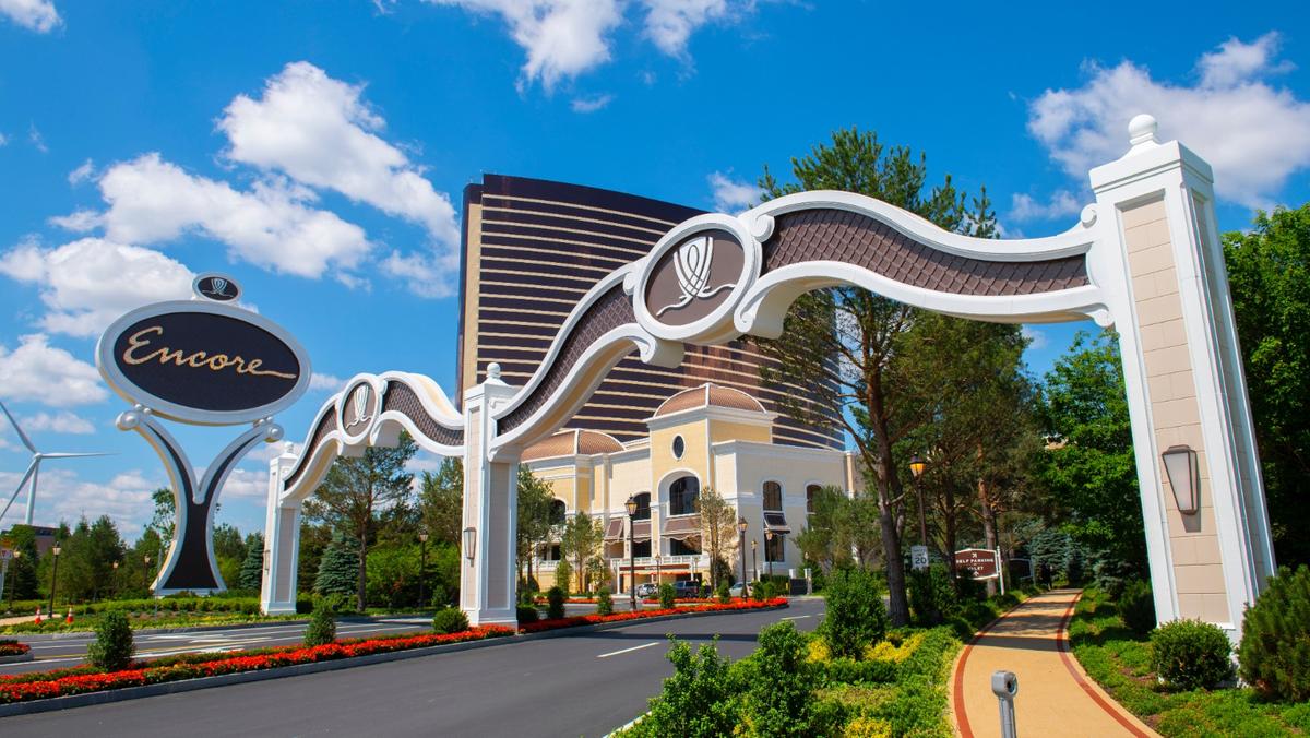 The entrance archway and sign of the Encore Boston Harbor resort with its bronze hotel tower in the background.