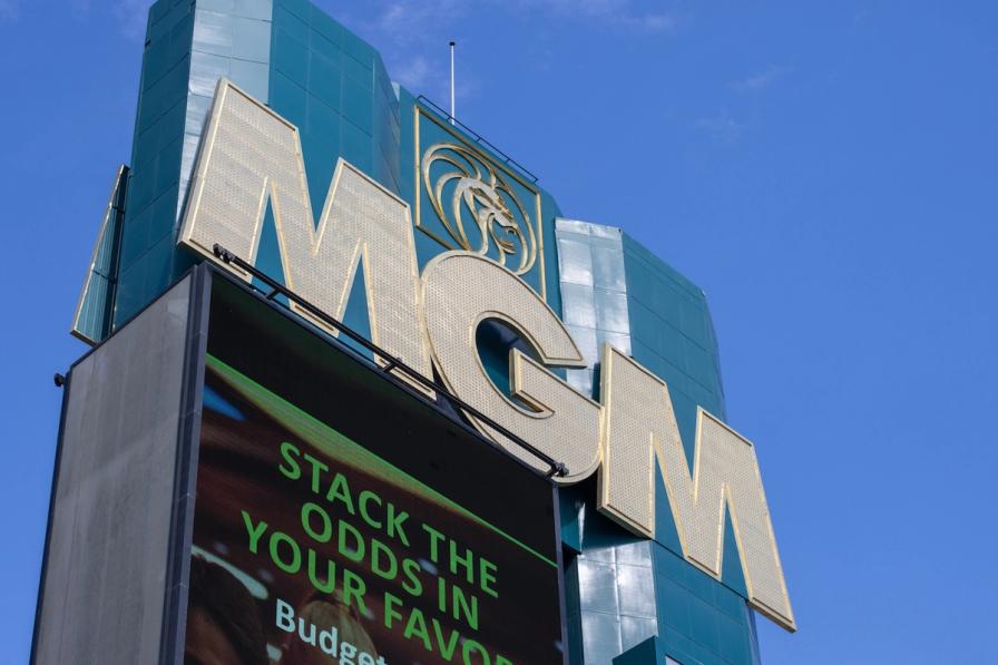 Large gold MGM sign and lion logo on a teal building against a clear blue sky.