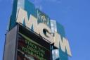 Large gold MGM sign and lion logo on a teal building against a clear blue sky.