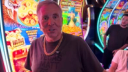 Vegas Matt wearing a gold chain and standing in front of colorful slot machines in a casino.