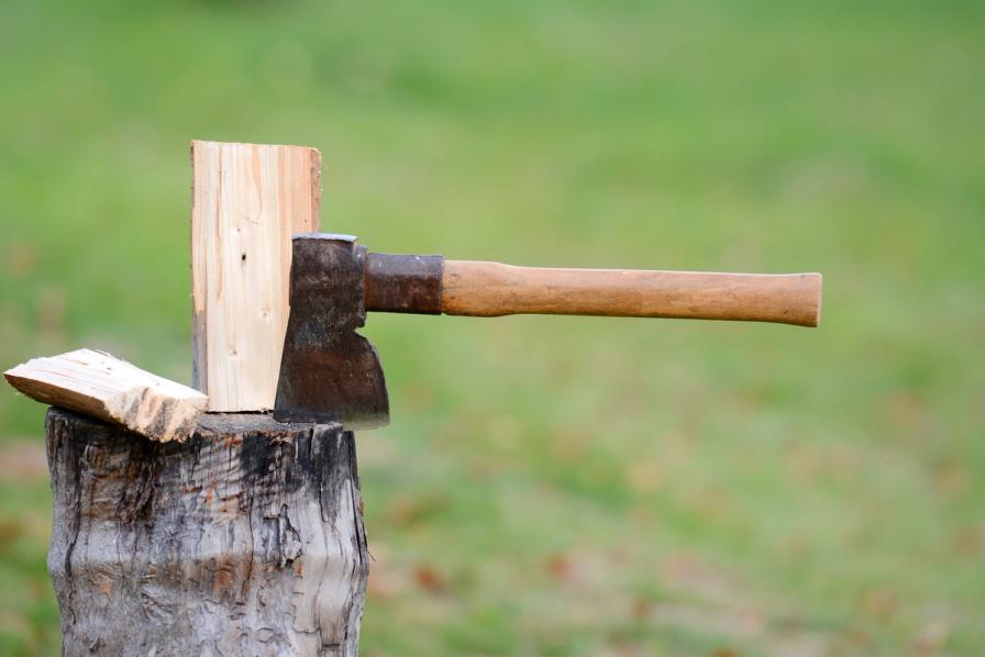 An axe embedded in a piece of wood on a chopping block.