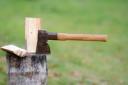 An axe embedded in a piece of wood on a chopping block.
