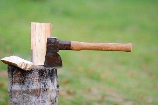 An axe embedded in a piece of wood on a chopping block.